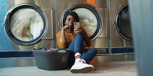 Woman looking at mobile phone in a laundromat